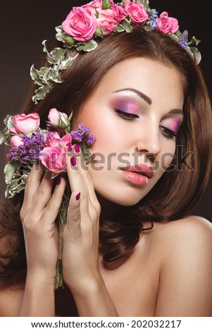 Beautiful girl with perfect skin and bright floral wreath on her head. Picture taken in the studio on a black background