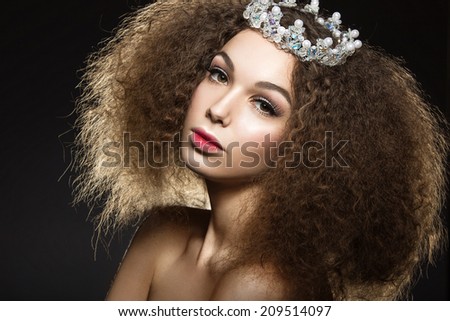 Beautiful girl with a crown in the form of a princess. Picture taken in the studio on a black background.