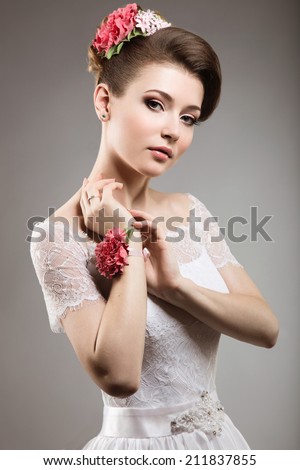 Portrait of a beautiful woman in the image of the bride with flowers in her hair. Picture taken in the studio on a grey background