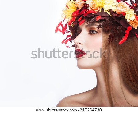 Beautiful red-haired girl with bright autumn wreath of leaves and flowers. Beauty face. Picture taken in the studio on a white background.