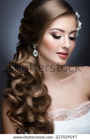 Portrait of a beautiful woman in a wedding dress in the image of the bride. Picture taken in the studio on a grey background
