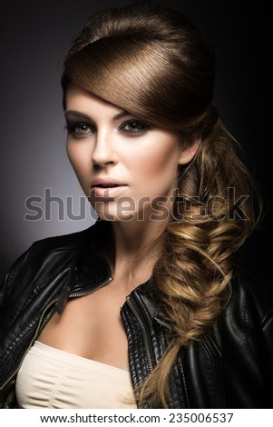 Beautiful girl with bright make-up, perfect skin and hairstyle as a braid.Picture taken in the studio on a gray background