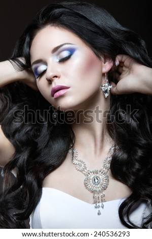 Elegant beautiful girl with silver makeup and black curls. Winter image. Beauty face. Picture taken in the studio on a black background.
