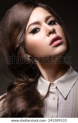 Beautiful girl with unusual black arrows on eyes and light lips. Beauty face. Picture taken in the studio on a black background.