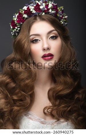 Beautiful  girl in the image of a bride with flowers in her hair. Beauty face. Wedding image. Picture taken in the studio on a grey background.