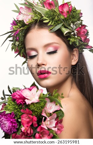 Beautiful girl with a lot of flowers in their hair and bright pink make-up. Spring image. Beauty face. Picture taken in the studio on a white background.