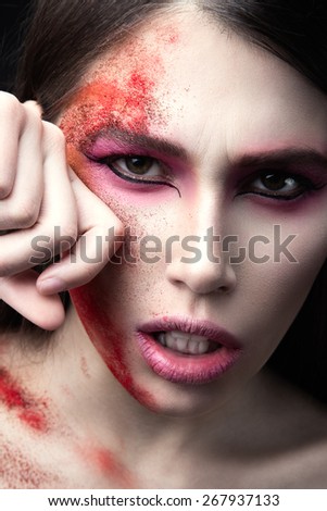 Portrait of a beautiful Girl with red paint on her face. Art beauty image. Photo shot in the Studio on a black background.