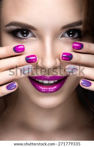 Beautiful girl with a bright evening make-up and purple manicure with rhinestones. Nail design. Beauty face. Picture taken in the studio on a black background.