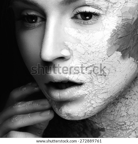 Beautiful girl with mud on his face. Cosmetic mask. Beauty face. Picture taken in the studio on a black background. Black&white photo