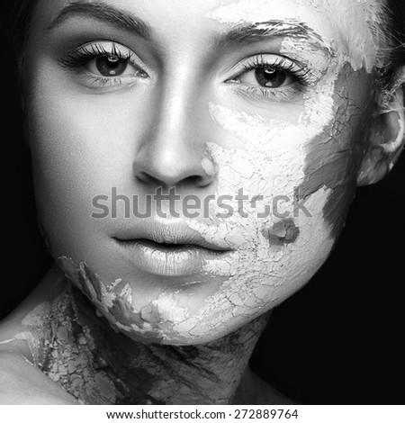 Beautiful girl with mud on his face. Cosmetic mask. Beauty face. Picture taken in the studio on a black background. Black&white photo