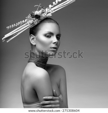Beautiful girl with a bronze skin, pale makeup and unusual accessories. Art beauty image. Beauty face. Picture taken in the studio. Black and white photo.