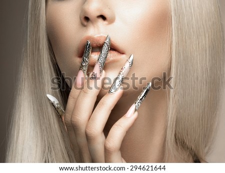 Beautiful fashionable girl in a glamorous image with bright makeup and long silver nails. Art design manicure. Picture taken in the studio.