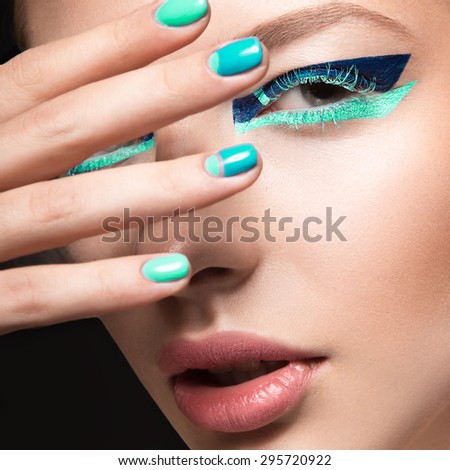Beautiful girl with bright creative fashion makeup and green nail polish. Art beauty nail design. Picture taken in the studio.