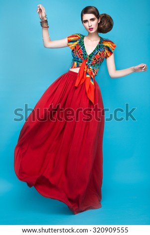 Beautiful fashionable woman an unusual hairstyle in bright clothes and colorful accessories. Cuban style. Picture taken in the studio on a bright background.