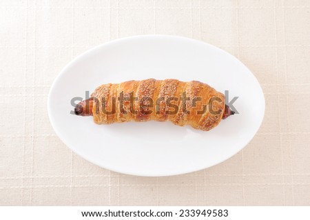sausage roll bread on plate on table cloth