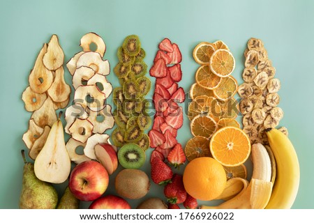 Dried fruits and fruit chips along with the fresh fruit of which they are made. Dietary nutrition. Natural and healthy snack food.