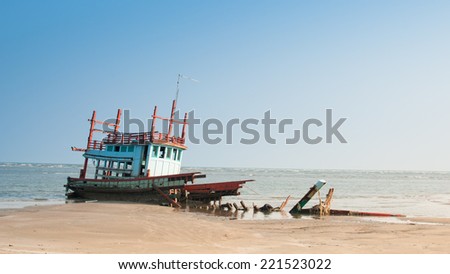 Small boat washed up on shore, bright blue sky in background