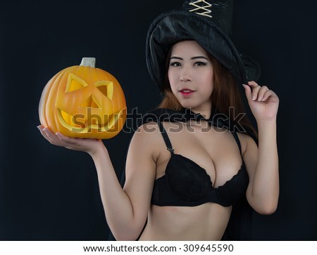 Woman in witch Sexy costume opens carved Halloween pumpkin