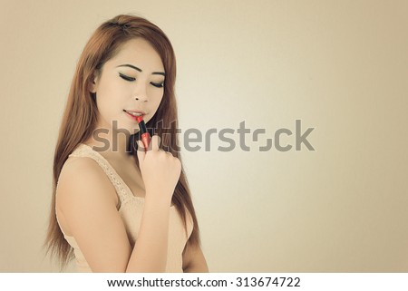 beautiful woman is applying her lips with pink lipstick,Woman with lipstick,vintage