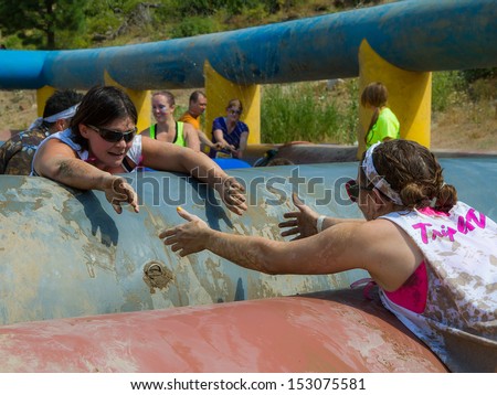 BOISE, IDAHO/USA - AUGUST 11: Two runners try to help each other over the obstacles at the The Dirty Dash in Boise, Idaho on August 11, 2013