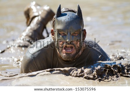 BOISE, IDAHO/USA - AUGUST 10: Runner dressed as batman swims in the mud during the The Dirty Dash in Boise, Idaho on August 10, 2013