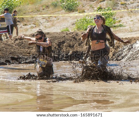 BOISE, IDAHO/USA - AUGUST 10:Two runners running fast and making a splash in the mud pit during the The Dirty Dash in Boise, Idaho on August 10, 2013