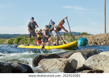 CASCADE, IDAHO/USA - JUNE 21, 2014:SUPsquatch with a group of people working it\'s way through the river.