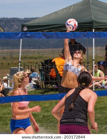 CASCADE, IDAHO/USA - JUNE 21, 2014: Woman spikes a ball over the net at the Payette River Games Volleyball Tournament in Cascade, Idaho