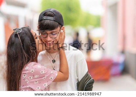 Focus on a young latina woman kissing the cheek of a friend while embracing him int he street Imagine de stoc © 