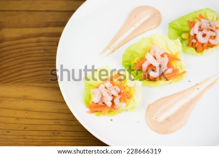 Fresh prawn or shrimp layered salad with Mary Rose dressing on a wood textured background. Healthy and tasty food recipe for a balanced nutrition.