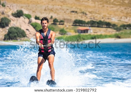 Handsome young man waterskiing on the sea. Happy man on holiday doing water sports and having fun. Holiday abroad on an island.