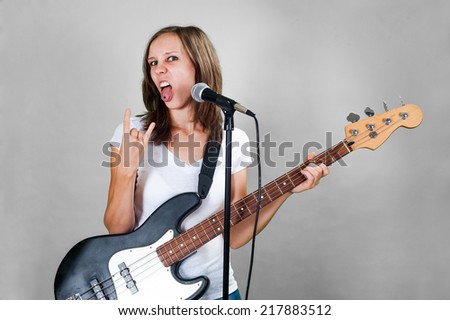 Rock girl with mic and bass guitar isolated on gray background