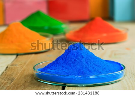 The pile of powder coating on glass plate, on wooden background.