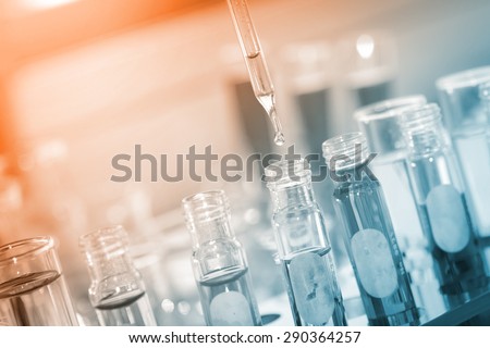 A researcher dropping the clear reagent into test tube for reaction testing in chemical laboratory.