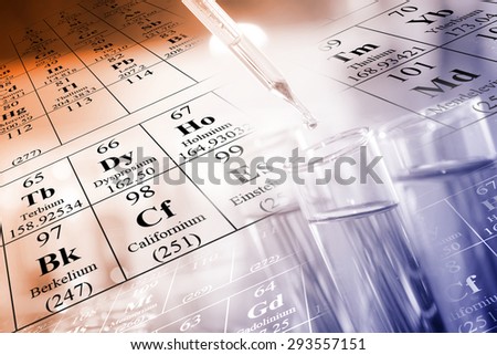A researcher dropping the clear reagent into test tube with periodic table and chemical equations background, for reaction testing in chemical laboratory.
