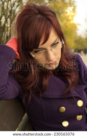 Sad young woman waiting for someone on a bench in the park