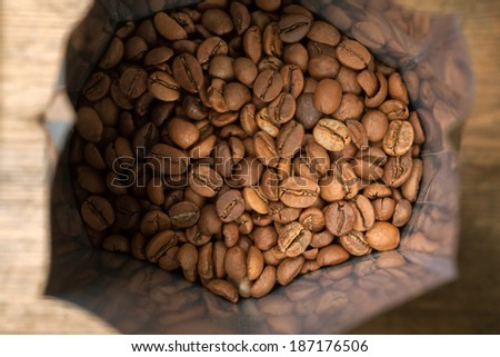 Coffee beans in aluminum foil bag package on wooden surface