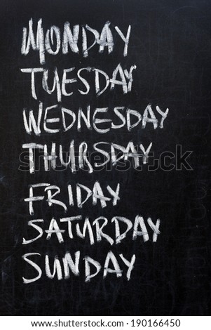 Conceptual weekdays list written on black chalkboard blackboard. Monday Tuesday Wednesday Thursday Friday Saturday Sunday.