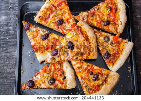 Sliced home made pizza on wooden rustic background