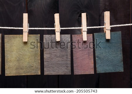 Close up of wooden notes attach to rope with clothes pins on dark wooden background