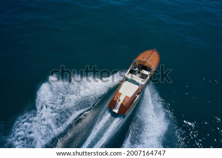 Classic Italian wooden boat fast moving aerial view. Top view of a wooden powerful motor boat. Luxurious wooden boat fast movement on dark water. Stock fotó © 