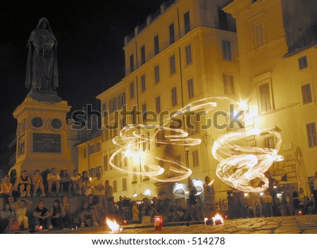Jugglers with fire, in the square of flowers (campo dei fiori) in rome italy with the statue of Giordano Bruno (a philosopher who was set on fire in this square by the church for his thoughts)