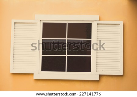 Vintage window on yellow cement wall