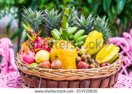 A big variety of exotic fruits in a basket on green background
