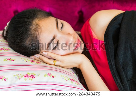 Beautiful asian woman taking a nap on sofa with red dress