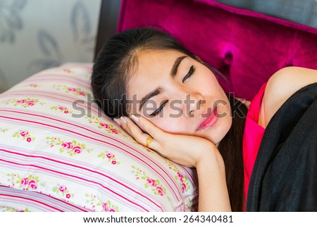 Beautiful asian woman taking a nap on sofa with red dress