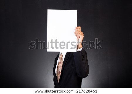A business man holding a paper in front of his face
