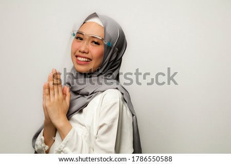 Young Asian Muslim new greeting for Eid Mubarak / Ied Fitr / Eid Al-Fitr and Eid Al-Adha celebration in new normal era with face shield Imagine de stoc © 