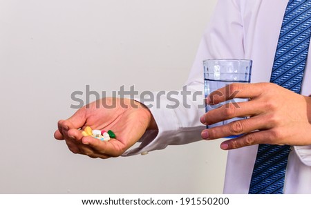 man holding pills medicine drinking water to eat.