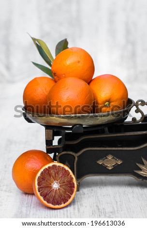Red sicilian oranges on vintage kitchen scales with white wooden background